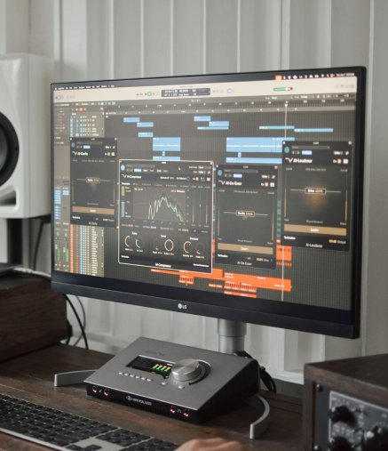 Music production desk with DAW on monitor.